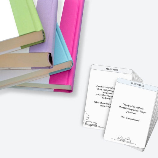 A stack of book club discussion question cards beside a pile of books.